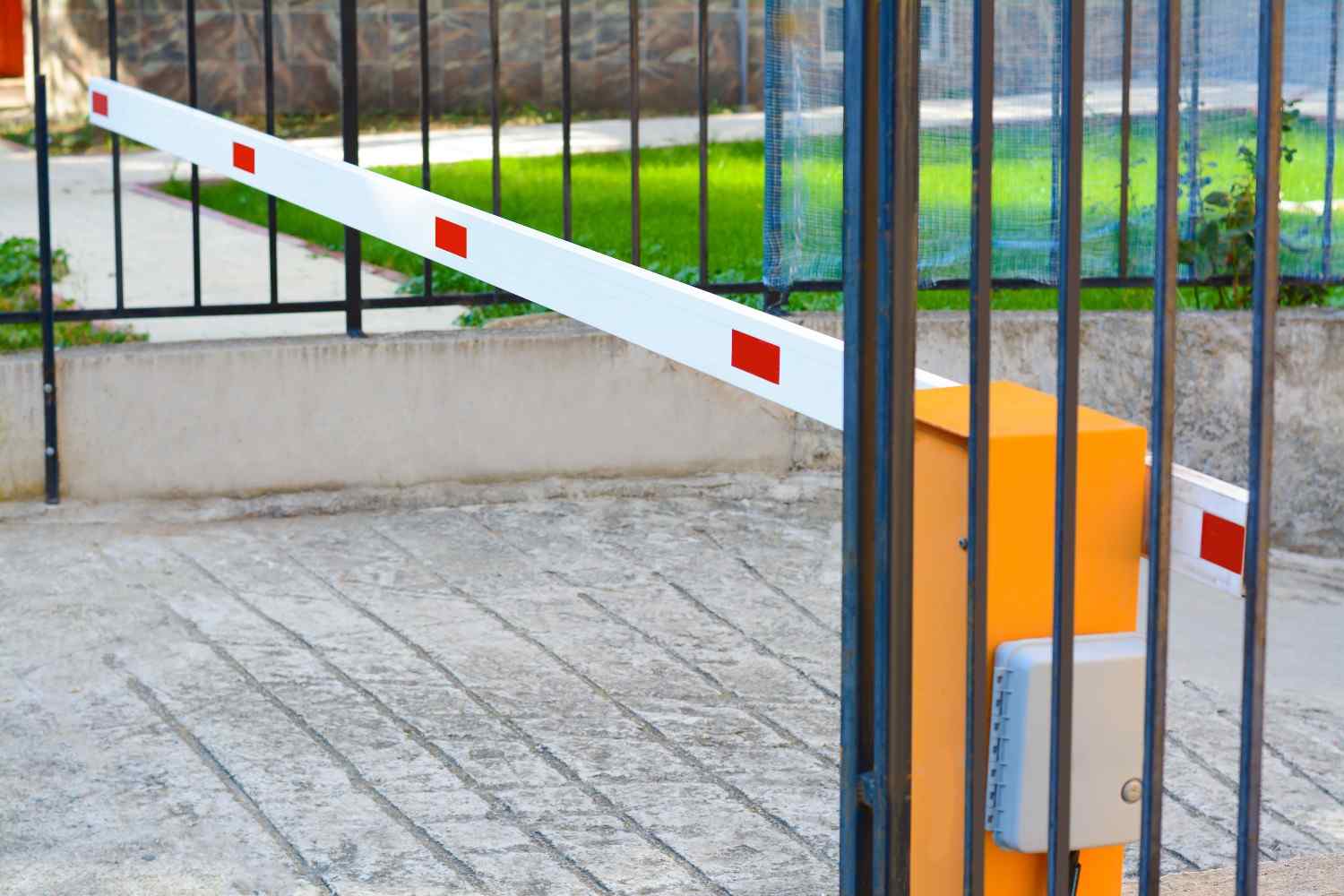 White barrier arm with red reflective strips blocking a paved entrance.