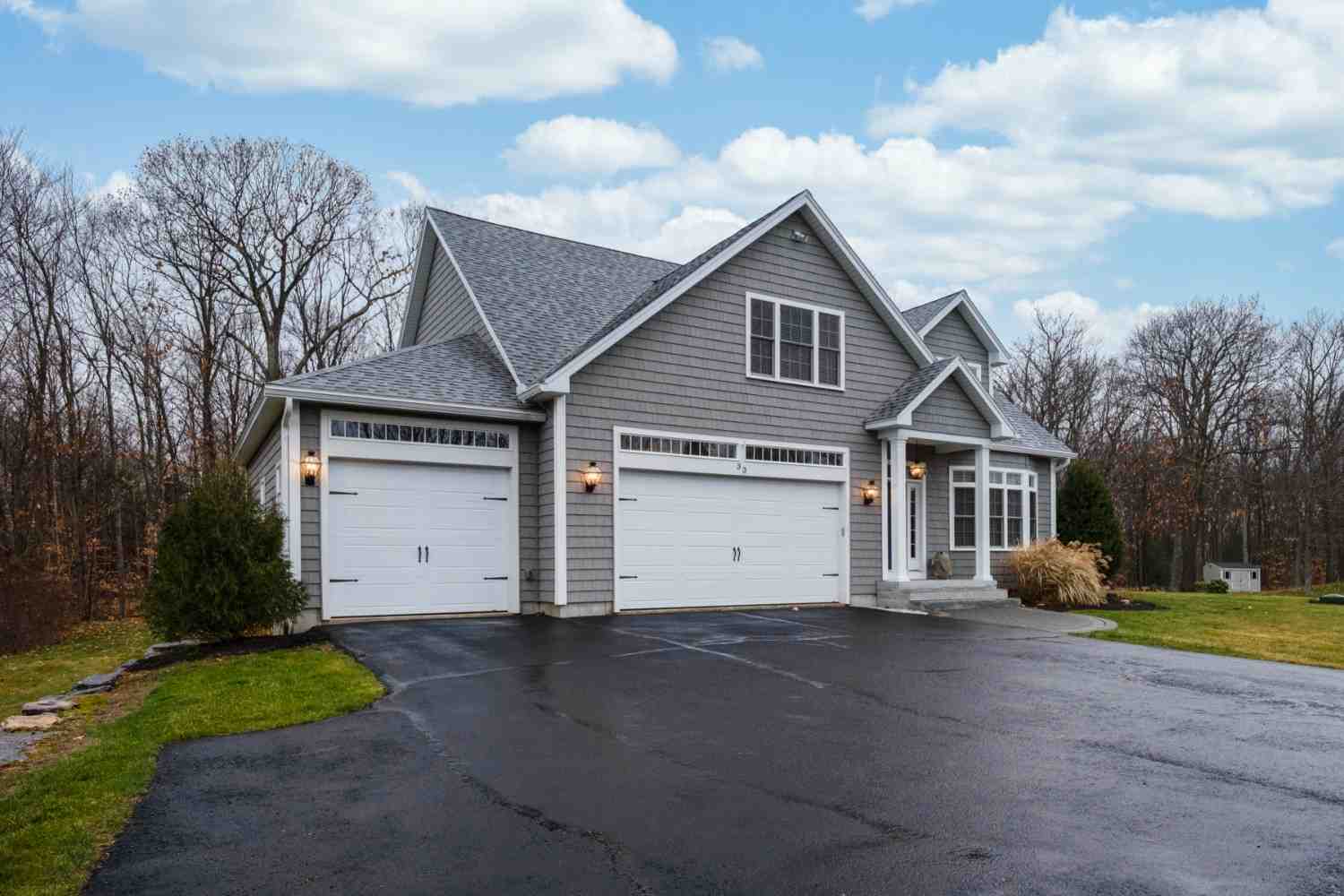 Gray house with two white garage doors and a paved driveway