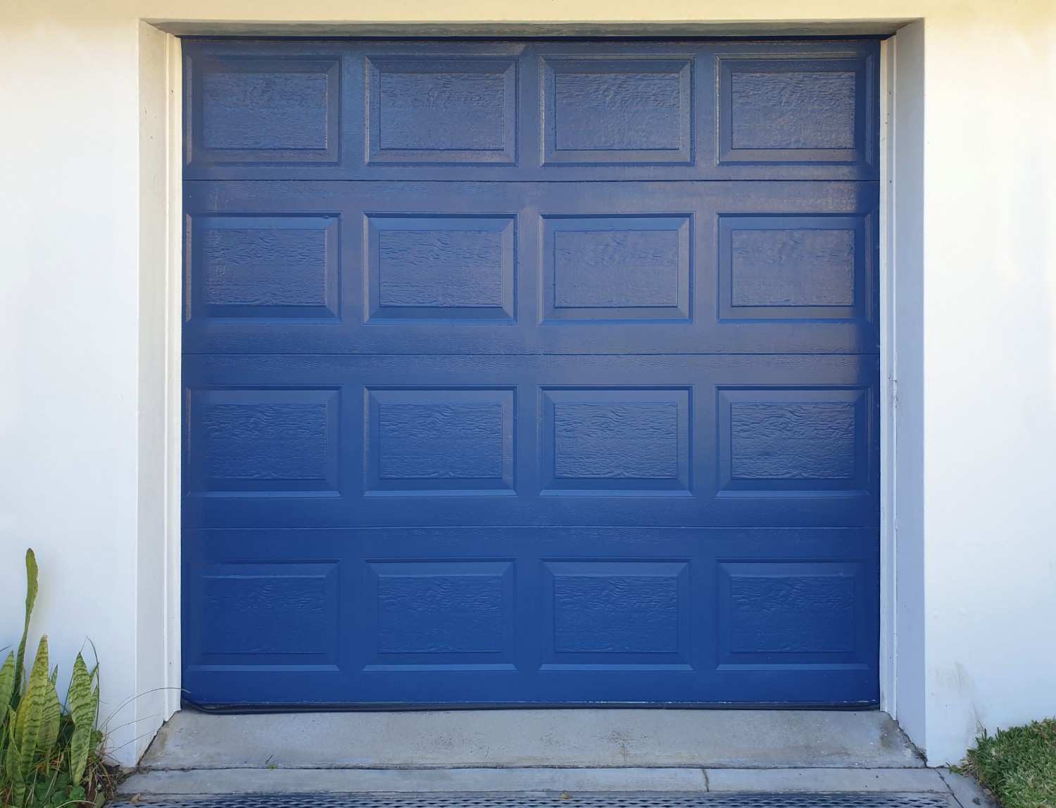 A closed blue garage door with rectangular panels and a textured finish.