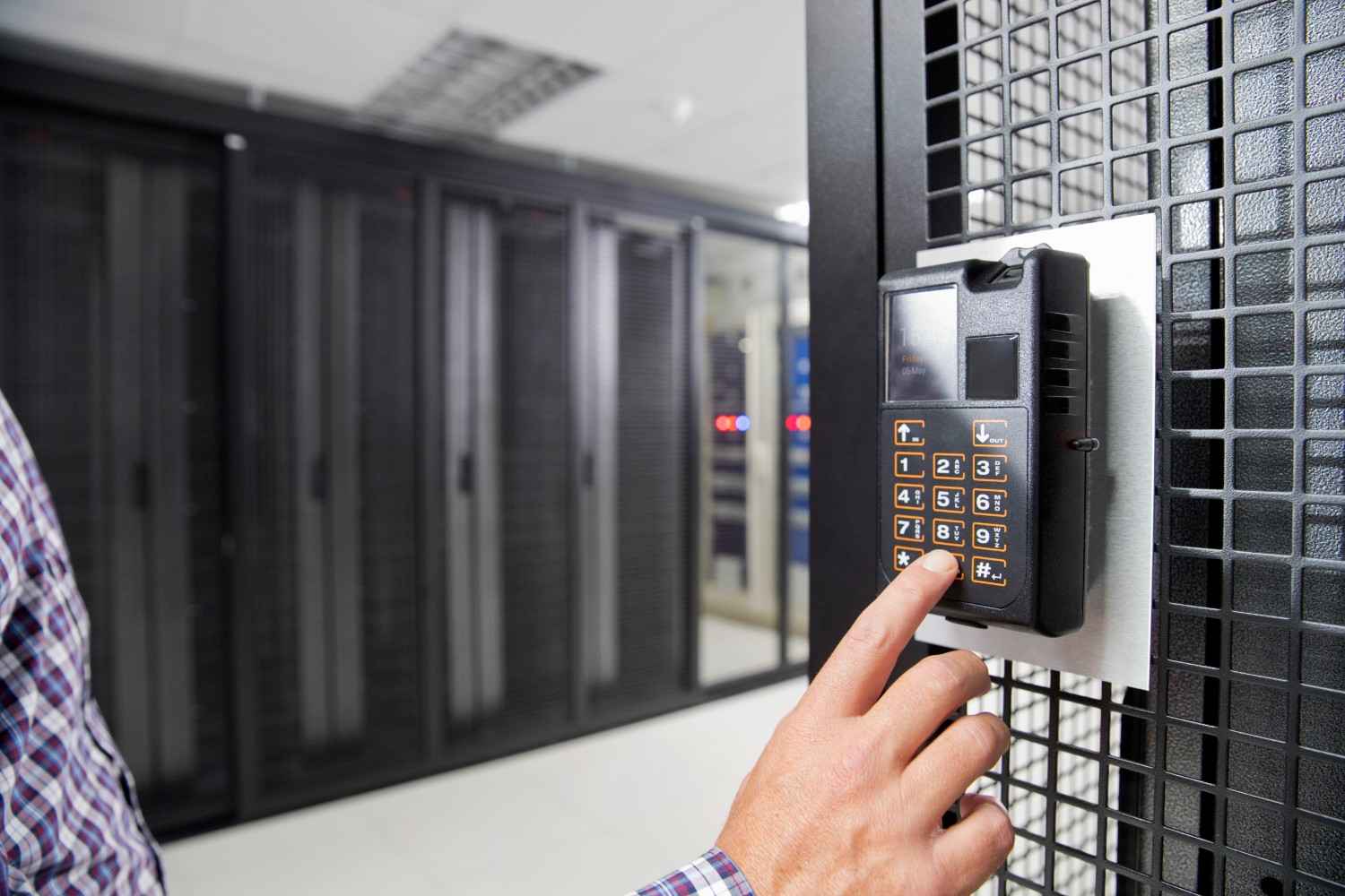 Hand entering code on a security keypad in a server room