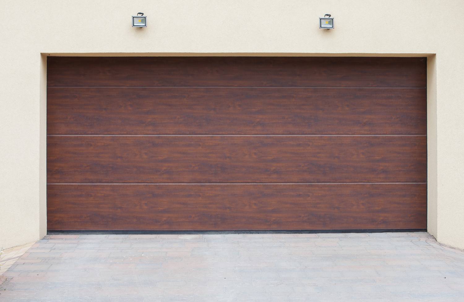 Closed brown garage door with horizontal panels on a beige wall.