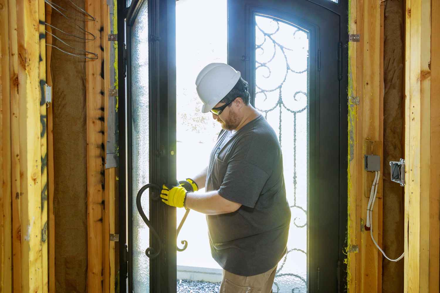 Man in hard hat and gloves installing a decorative metal door
