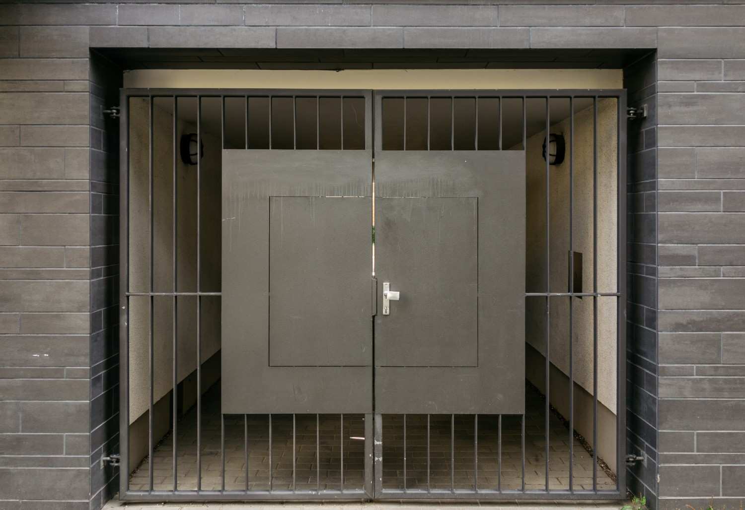 Dark gray metal gate in front of a building entrance with two doors