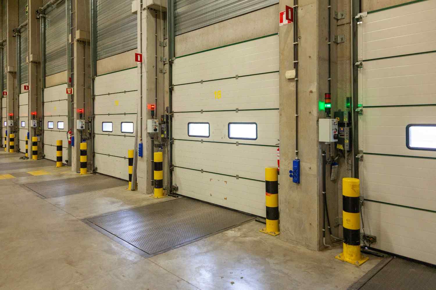 Row of white loading dock doors with yellow and black bollards