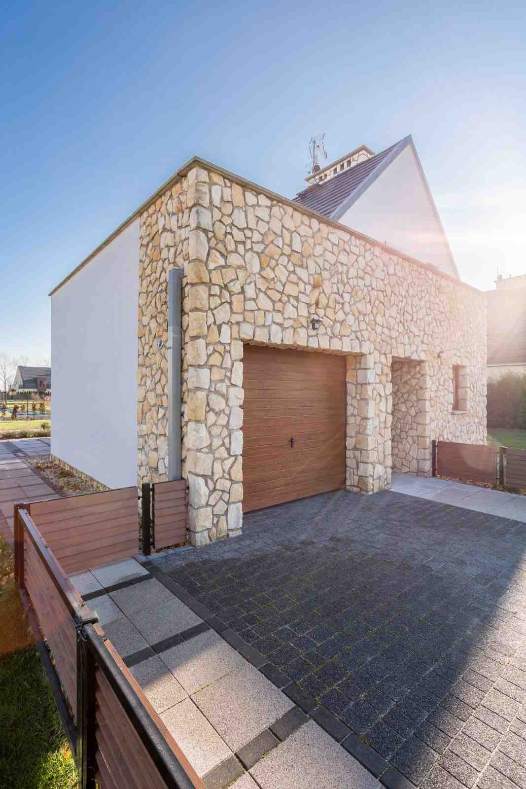 Modern house with stone facade, wooden garage door, and paved driveway